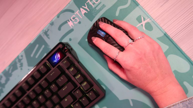 TechGirlZA holding the ROG Harpe Ace Extreme, showing its real carbon fibre shell.